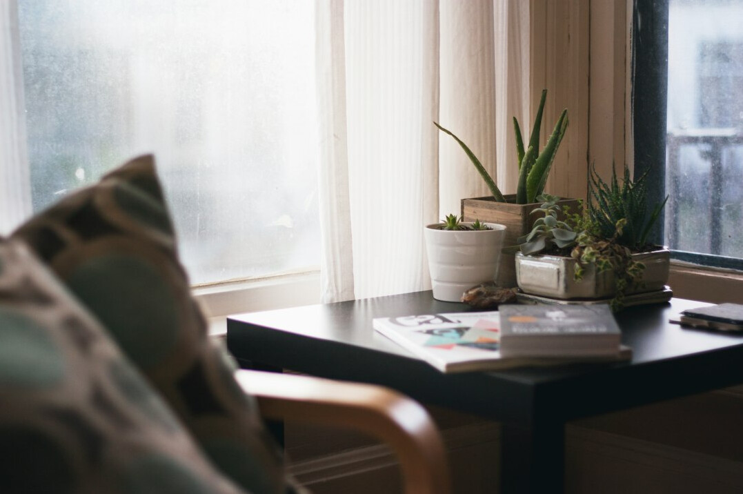 Desk with laptop, plant and notebook near a window