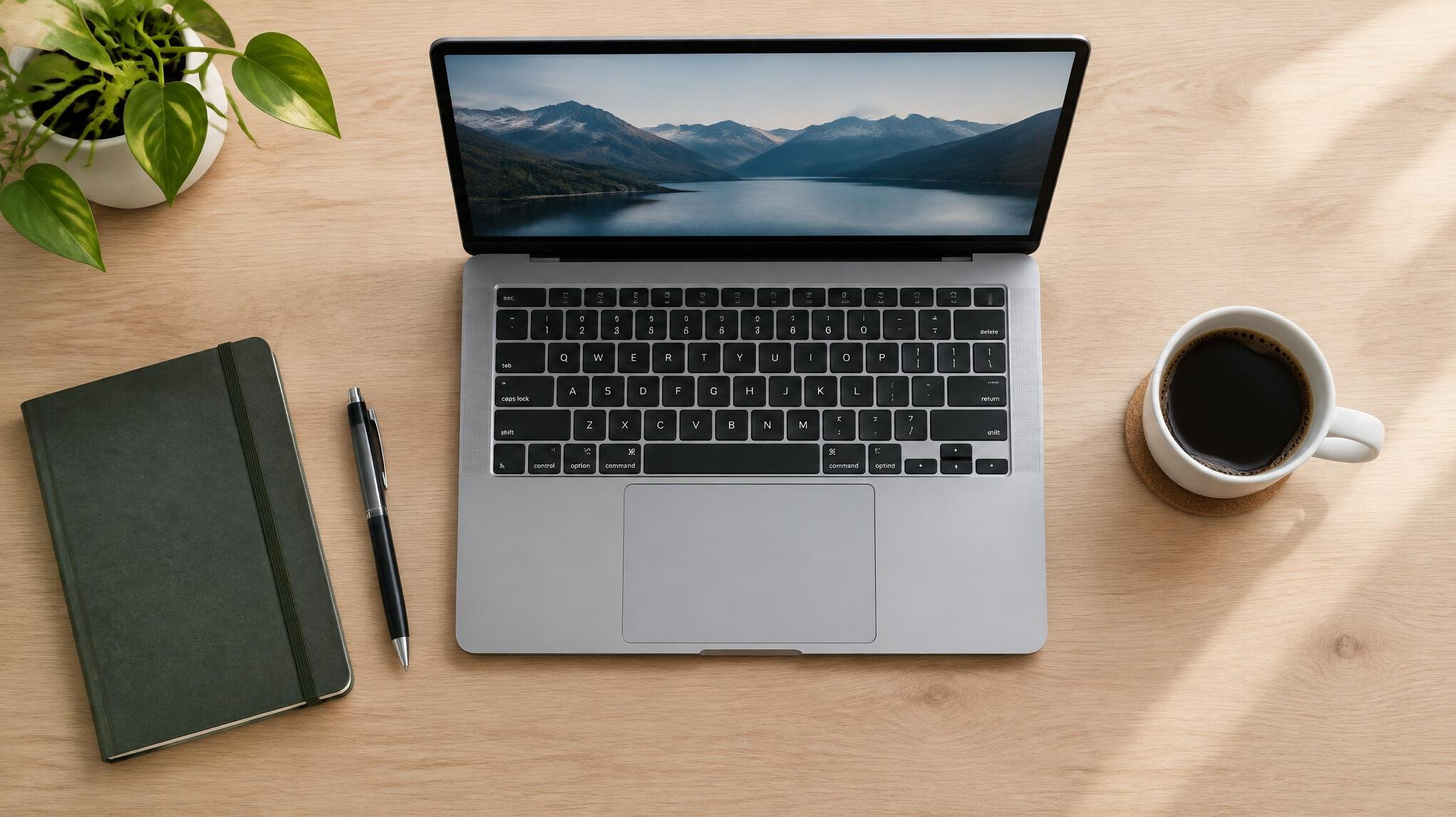 Flat lay of a laptop, notebook and coffee cup on a wooden desk